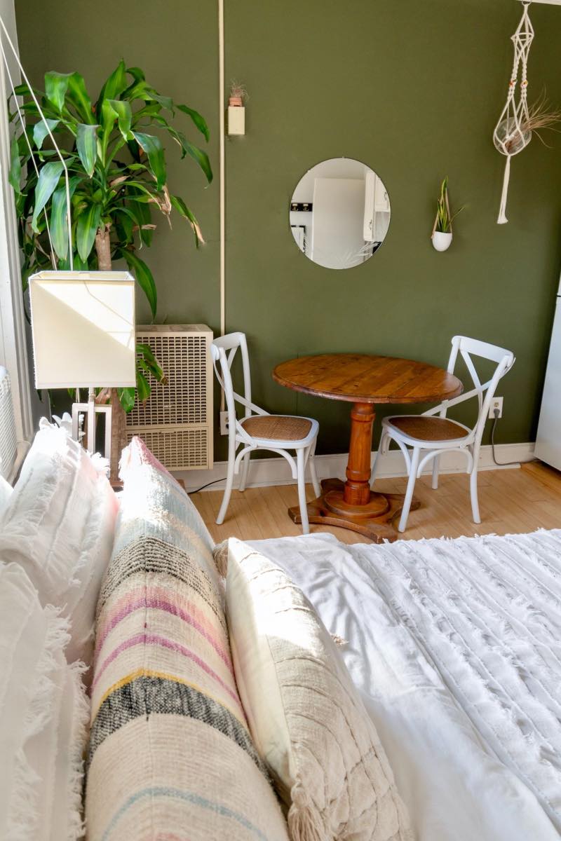 decoración maximalista con cama blanca y pared verde, dormitorio