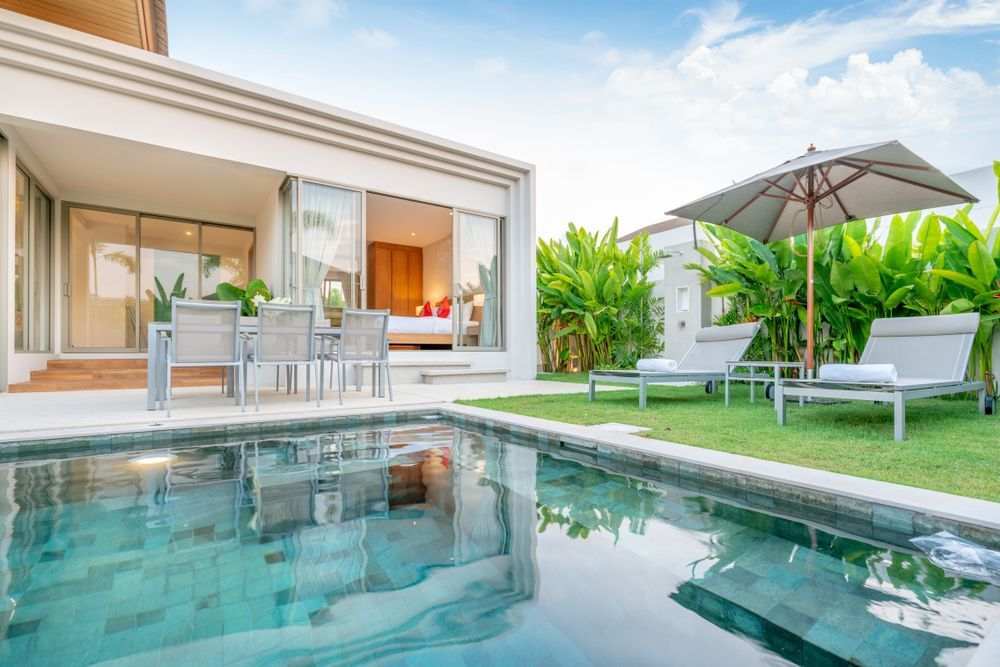 casa com piscina no jardim externo com duas espreguiçadeiras e guarda sol