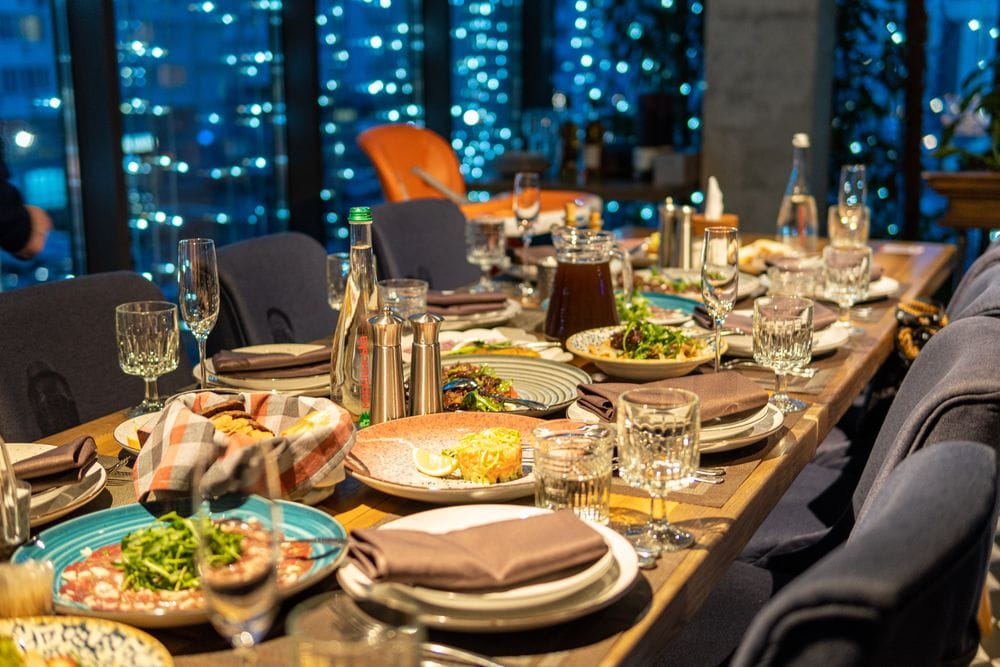 Mesa de jantar de madeira com poltronas cinzas decorada para jantar