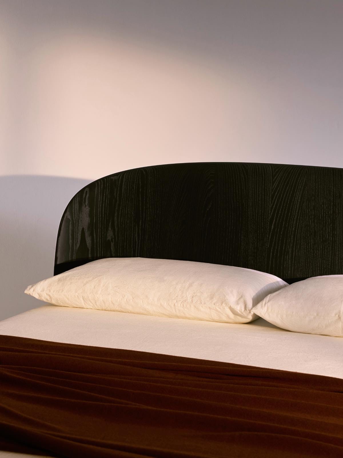 cama de matrimonio de madera negra con almohadas dobles blancas