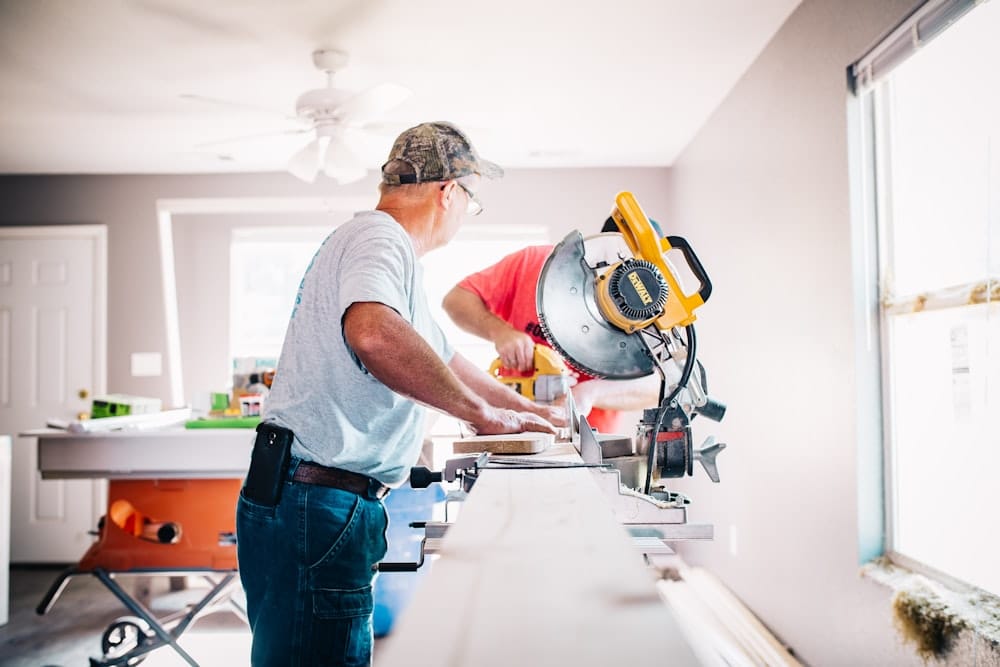 dois homens cortando móvel de madeira durante renovação dos móveis da casa