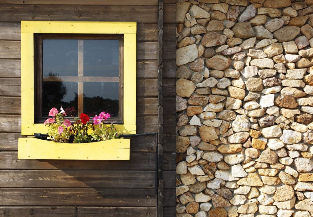 une façade de maison rustique avec une fenêtre jaune