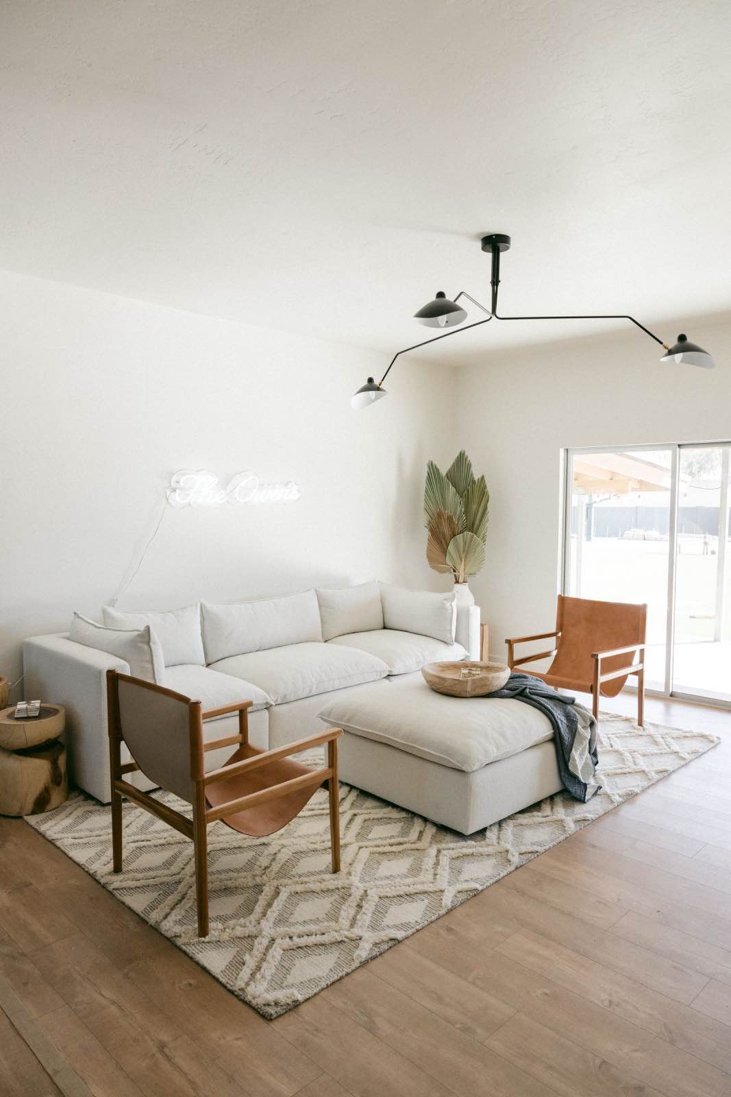 sala de estar de tonos neutros con sofá blanco y sillones marrones