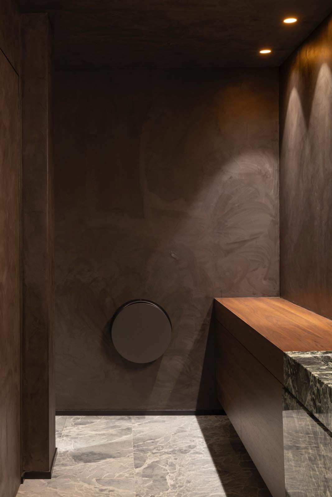 cuarto de baño de tonos neutros, paredes marrón oscuro, mármol, madera