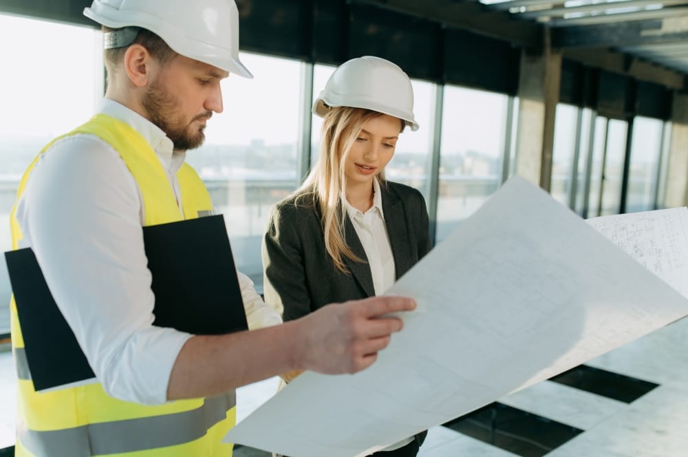 une femme consulte un ouvrier du bâtiment dans un intérieur