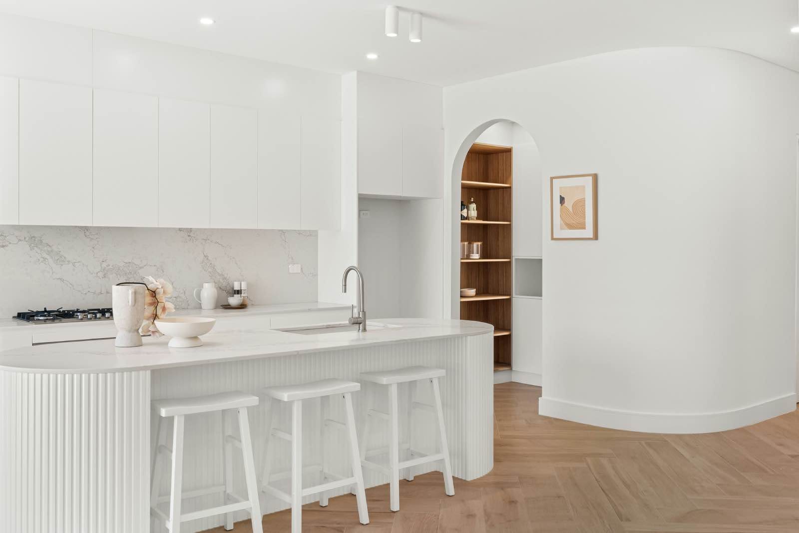 cocina blanca con isla y suelo de madera