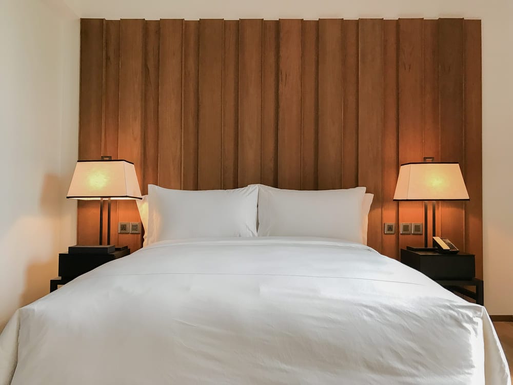 quarto com duas mesas de canto e dois abajures posicionados simetricamente