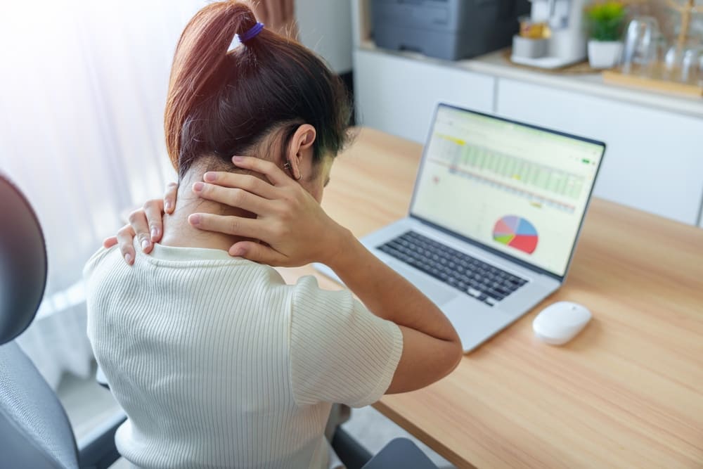 mulher com dores no corpo por conta de falta de ergonomia no trabalho