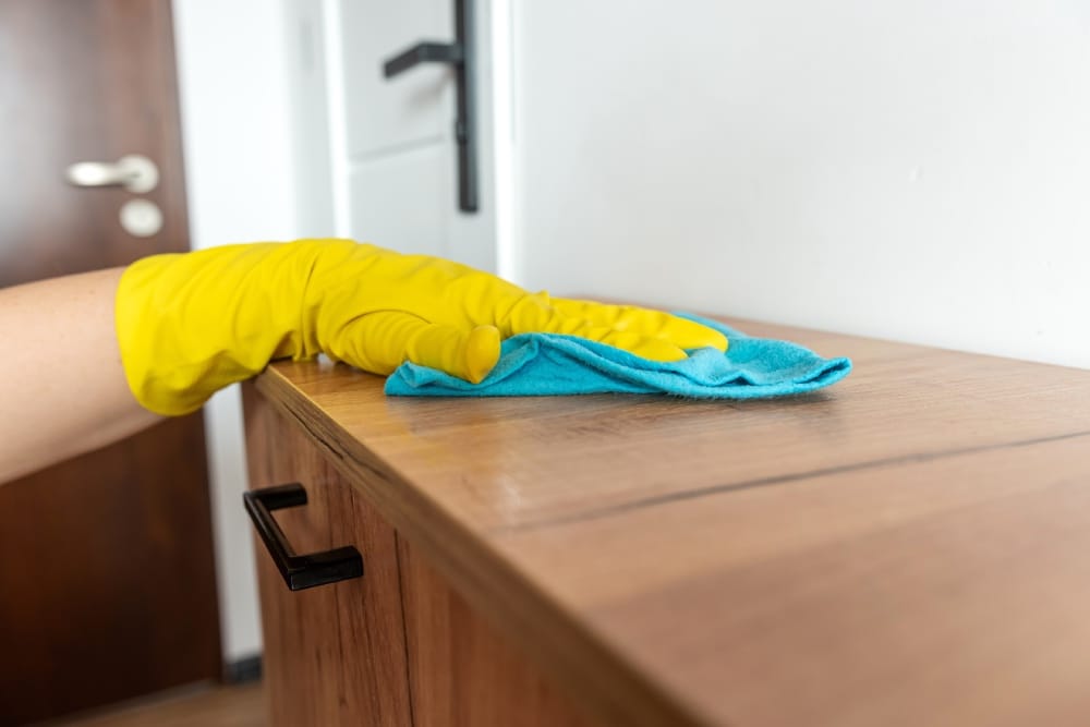 Holzmöbel-Pflege: Handschuhe aus Gummi anziehen und die Oberfläche der Holzmöbel mit einem feuchten Tuch abwischen.