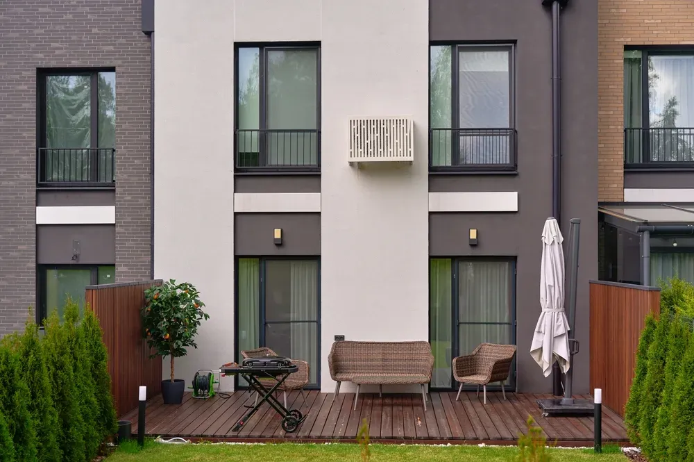 taras z meblami ogrodowymi wyposażony w drewniany pokład, wiklinowe siedziska i grill