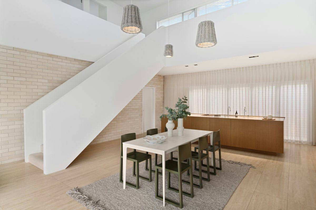 casa con techo de doble altura con escalera blanca. comedor y cocina moderna