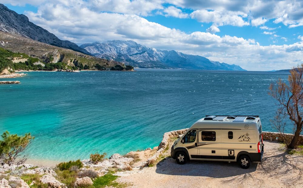 A modern European van conversion camping overlooking blue sea