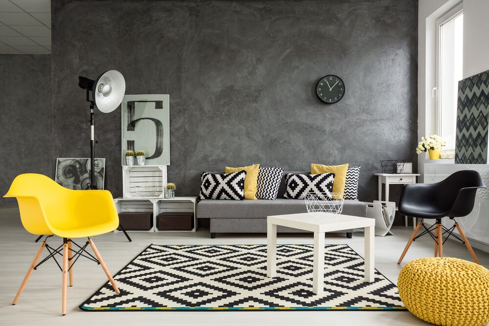 Grey living room with sofa, chairs, standing lamp, small table, yellow details and pattern decorations in black and white