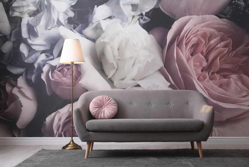 canapé gris contre un mur aux papiers peints floraux, couleurs roses