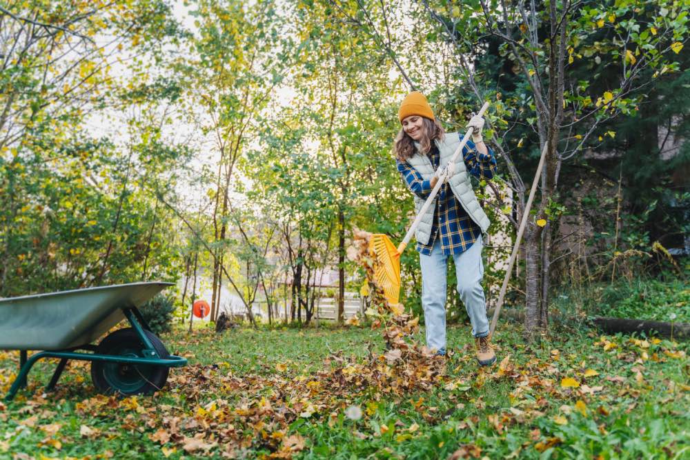 Frau beim Laubsammeln im Herbst