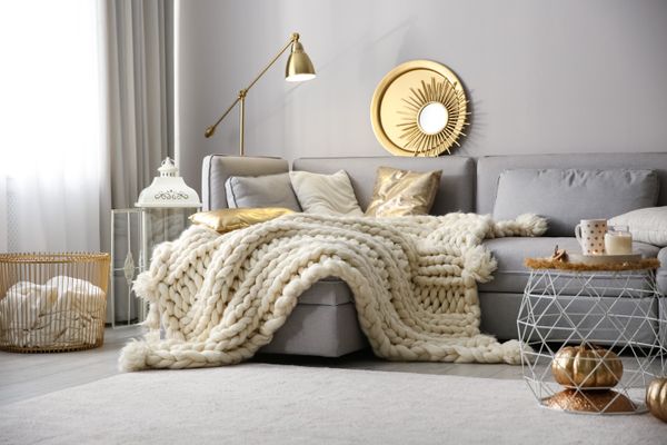 Cozy living room with knitted blanket on comfortable sofa