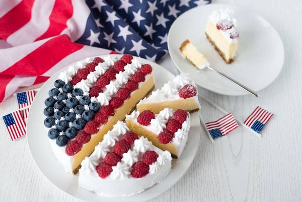 cheesecake in the cut with whipped cream and berry decoration on a white plate with usa flag