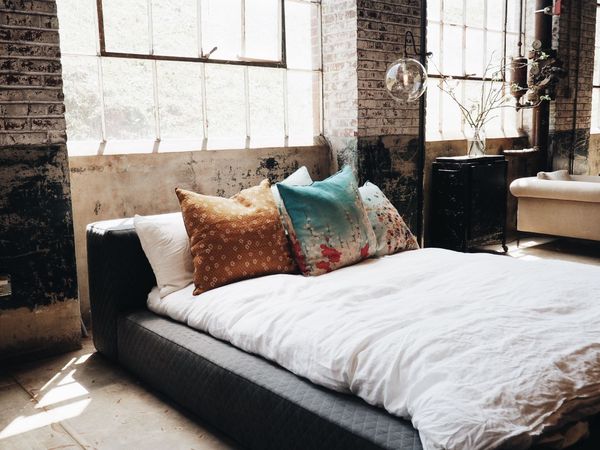 une chambre de style industriel avec des murs en briques, un lit double et des coussins  avec des motifs floraux