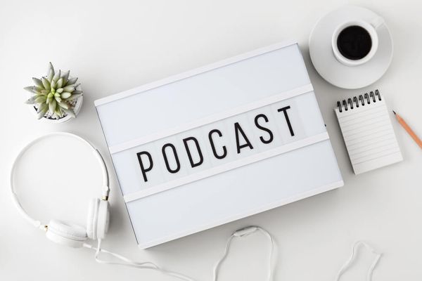 Podcast word on lightbox with headphones on white table