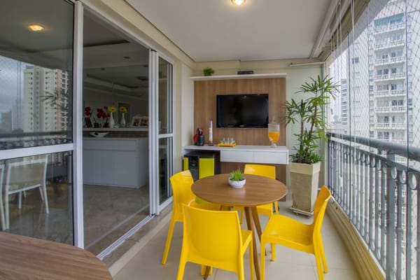 balcon de style brésilien avec une table ronde et 4 chaises jaunes