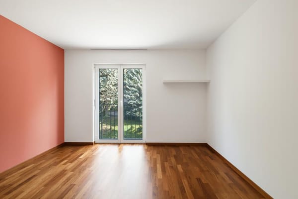 пустая комната с розовыми и белыми стенами и видом на зеленые деревья