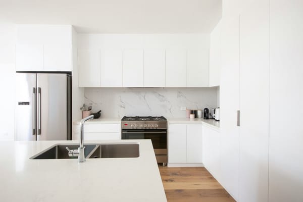 cocina blanca moderna minimalista con nevera de acero y salpicadero de mármol
