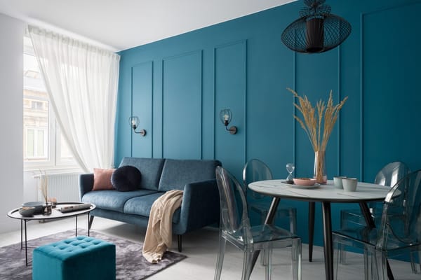 Stylish small living room with blue featured wall, couch and a small dining table