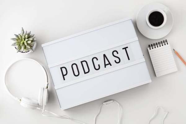 Podcast Wort auf Leuchtkasten mit Kopfhörer auf weißem Tisch
