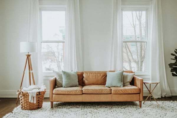 helles Wohnzimmer mit einem braunen Sofa und pastellfarbenen Kissen