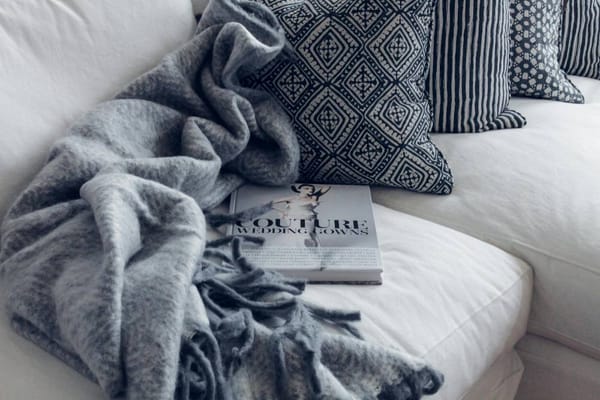 sofá branco com manta cinza decorativa e almofadas com desenhos cinzas