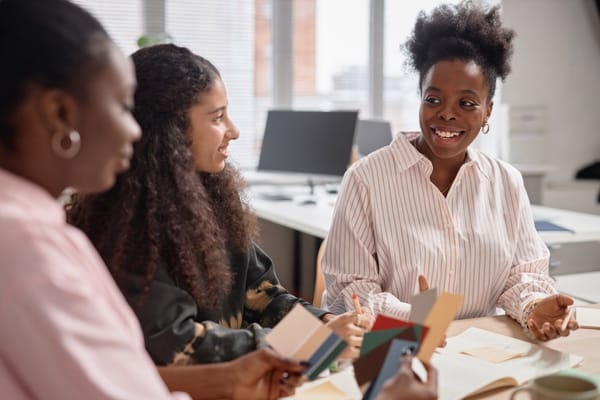 trois femmes noires se concertant autour d'un bureau