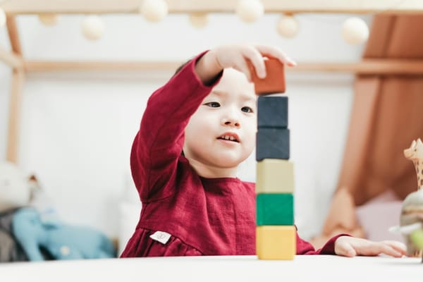 Asiatisches Kind spielt mit bunten Holzwürfeln